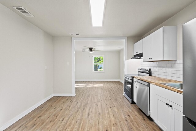 kitchen featuring tasteful backsplash, white cabinets, visible vents, stainless steel appliances, and under cabinet range hood