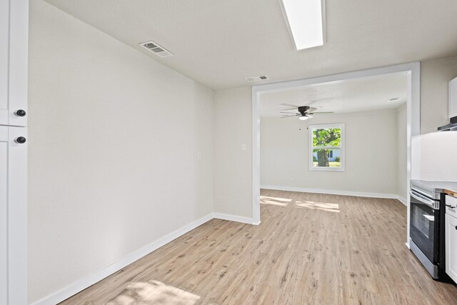 kitchen featuring wall oven, light wood finished floors, visible vents, and baseboards