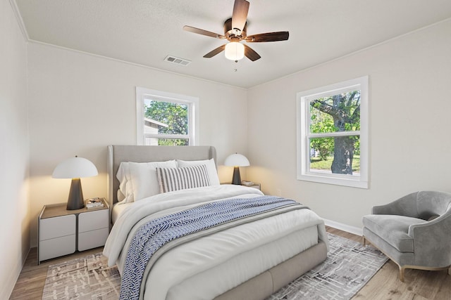 bedroom featuring wood finished floors, visible vents, and multiple windows