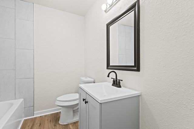 900 W Coffin St, Denison, TX 75020 - full bath with vanity, toilet, wood finished floors, a textured wall, and baseboards