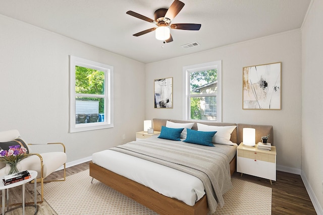 bedroom featuring visible vents, multiple windows, wood finished floors, and baseboards