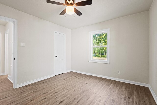 empty room with baseboards, wood finished floors, and ceiling fan