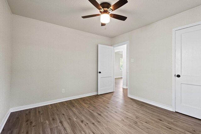 empty room featuring baseboards, wood finished floors, and a ceiling fan