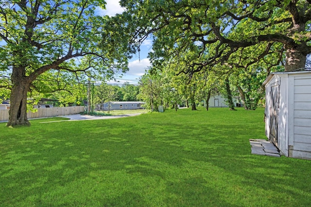 view of yard featuring fence, a storage unit, and an outbuilding
