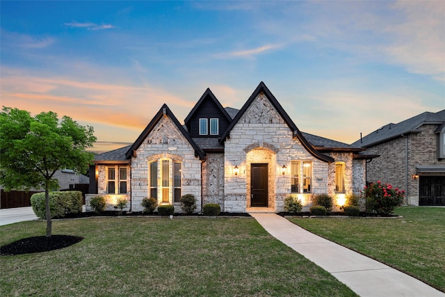 french provincial home featuring a front lawn and stone siding