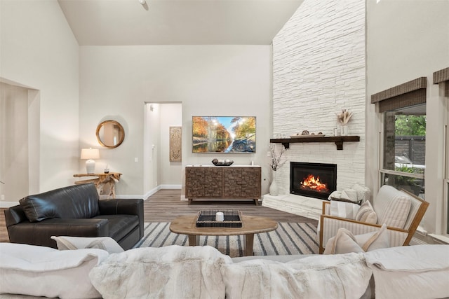 living room with a fireplace, high vaulted ceiling, wood finished floors, and baseboards