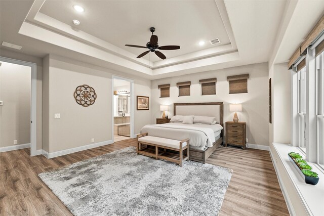 bedroom with recessed lighting, wood finished floors, baseboards, visible vents, and a tray ceiling