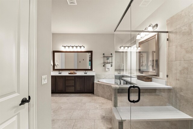 bathroom featuring tile patterned flooring, a bath, double vanity, and a sink