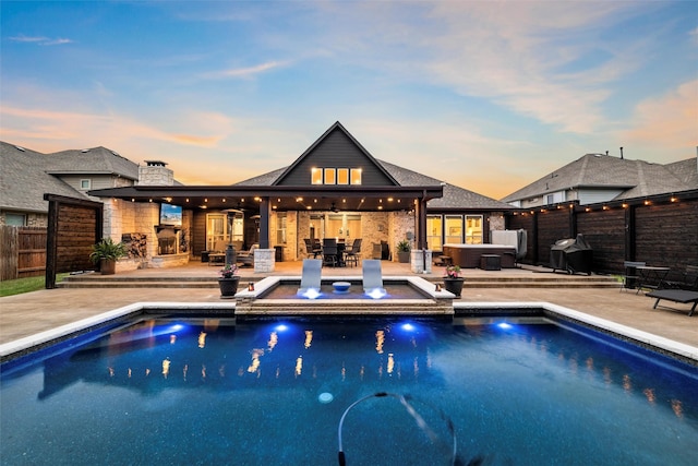 exterior space featuring fence, a hot tub, a fenced in pool, a patio area, and a grill