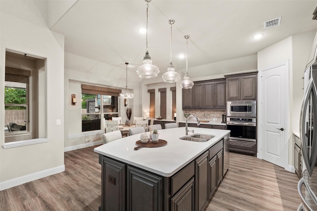 kitchen featuring a sink, decorative backsplash, stainless steel appliances, visible vents, and light countertops