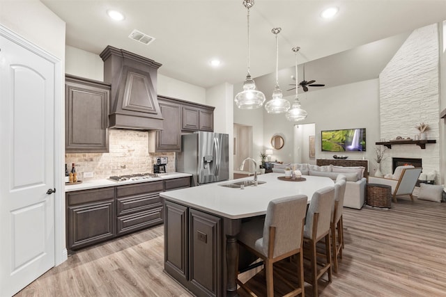 kitchen featuring custom range hood, appliances with stainless steel finishes, light countertops, backsplash, and a sink