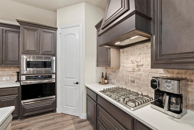 kitchen with dark brown cabinetry, light countertops, appliances with stainless steel finishes, and tasteful backsplash