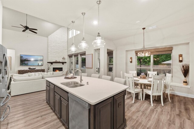 kitchen featuring a sink, stainless steel appliances, a fireplace, open floor plan, and ceiling fan with notable chandelier
