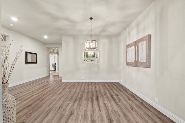 interior space with baseboards, wood finished floors, and an inviting chandelier
