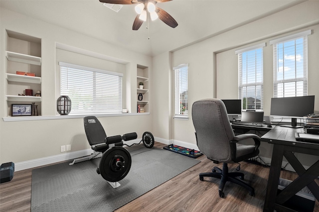 office space with wood finished floors, a ceiling fan, baseboards, and built in shelves