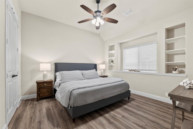 bedroom with wood finished floors, ceiling fan, baseboards, visible vents, and lofted ceiling