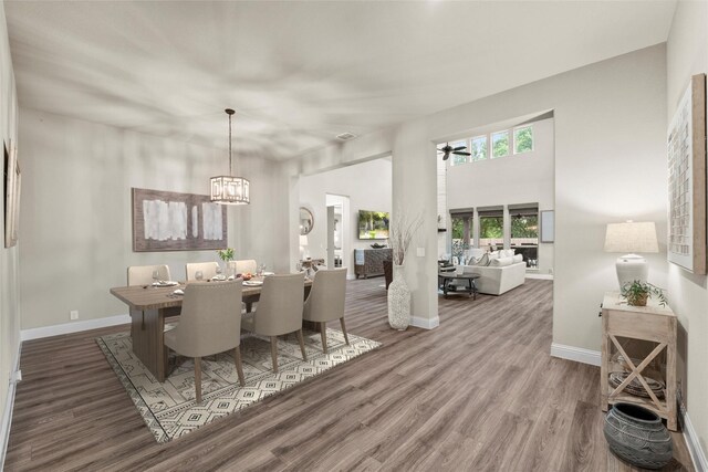 dining area featuring baseboards, wood finished floors, and ceiling fan with notable chandelier