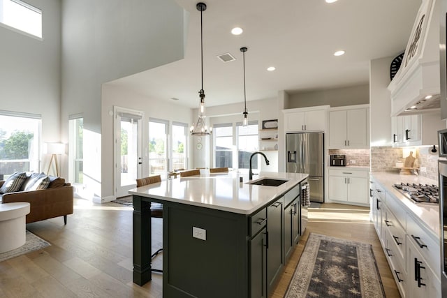kitchen with visible vents, a healthy amount of sunlight, a kitchen bar, a sink, and stainless steel appliances
