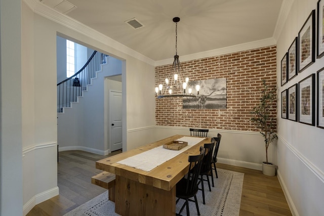 dining area featuring visible vents, stairs, wood finished floors, brick wall, and a chandelier