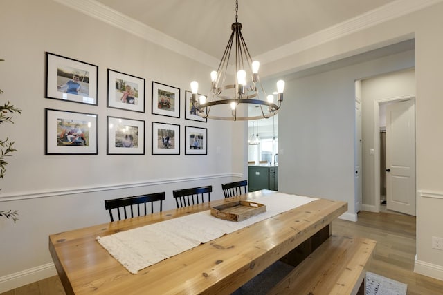 dining area with an inviting chandelier, baseboards, crown molding, and light wood-type flooring
