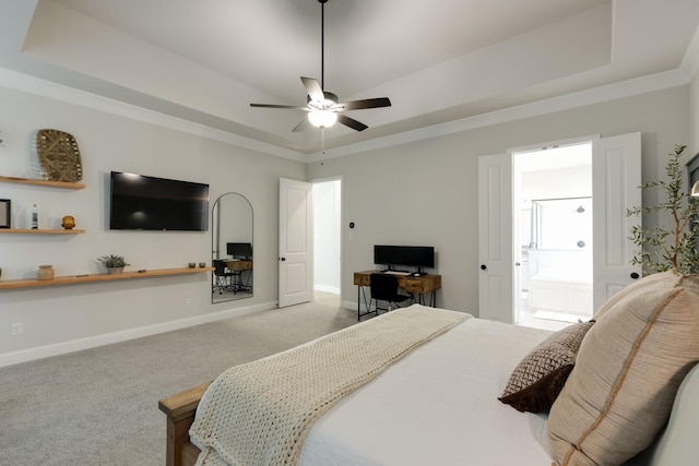 carpeted bedroom featuring a ceiling fan, a raised ceiling, baseboards, ornamental molding, and ensuite bath