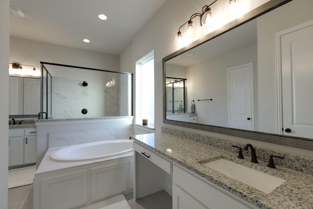 full bath featuring recessed lighting, a bath, two vanities, a sink, and a stall shower