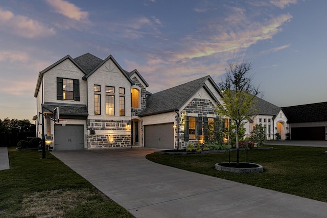 view of front facade with a lawn, concrete driveway, and stone siding