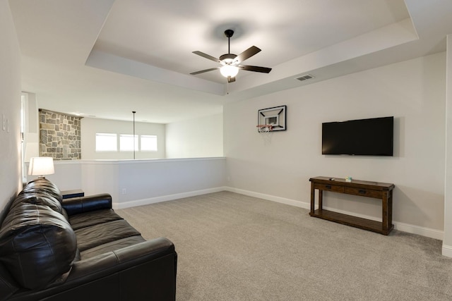 living area with carpet flooring, a raised ceiling, a ceiling fan, baseboards, and visible vents