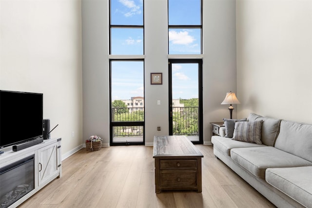 2608 Museum Way Unit 3407, Fort Worth, TX 76107 - living room featuring a towering ceiling, light wood-style flooring, and baseboards