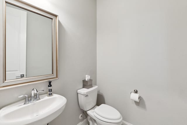 bathroom featuring a sink, toilet, and baseboards