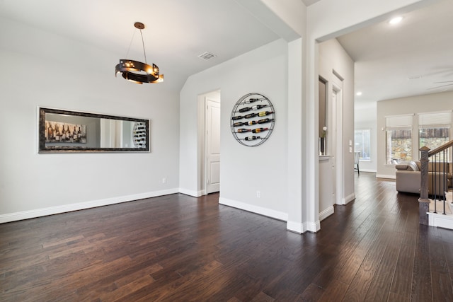 unfurnished dining area featuring dark wood finished floors, baseboards, recessed lighting, and a chandelier