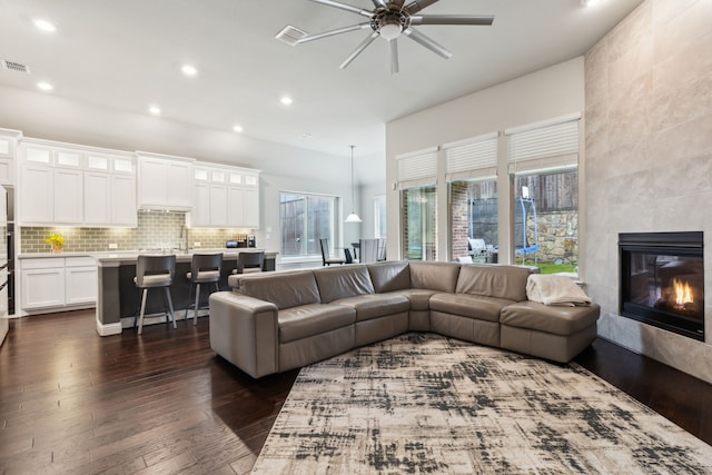 living room featuring dark wood finished floors, ceiling fan, recessed lighting, a high ceiling, and a fireplace