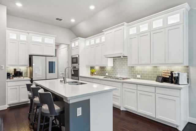 kitchen featuring stainless steel appliances, decorative backsplash, dark wood finished floors, vaulted ceiling, and a sink