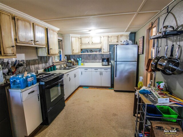 kitchen with freestanding refrigerator, light countertops, light carpet, a sink, and black range with gas cooktop