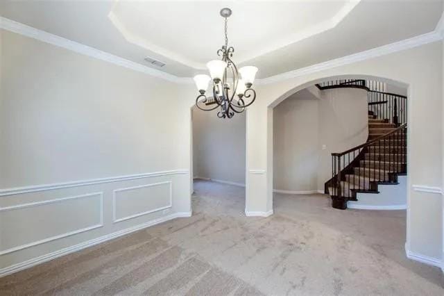 4502 Longbourn Dr, Mansfield, TX 76063 - unfurnished dining area with stairway, a notable chandelier, carpet, ornamental molding, and arched walkways