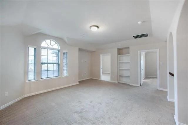 4502 Longbourn Dr, Mansfield, TX 76063 - empty room featuring lofted ceiling, visible vents, baseboards, and light carpet