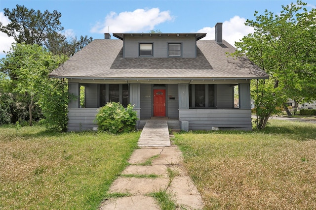 bungalow-style house featuring a chimney, a front lawn, and a shingled roof