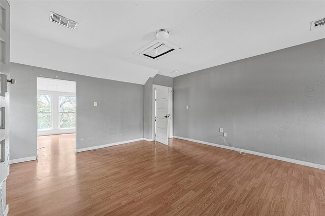 empty room with visible vents, vaulted ceiling, wood finished floors, and baseboards