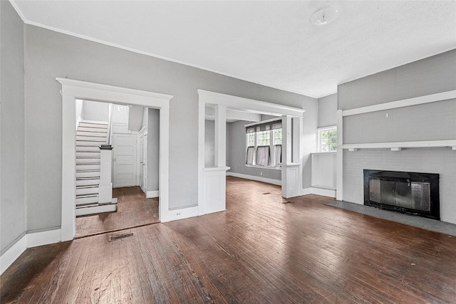 unfurnished living room with stairway, visible vents, hardwood / wood-style floors, baseboards, and a fireplace