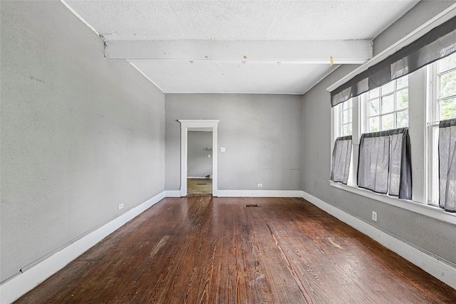 spare room featuring hardwood / wood-style floors, baseboards, lofted ceiling with beams, and a textured ceiling