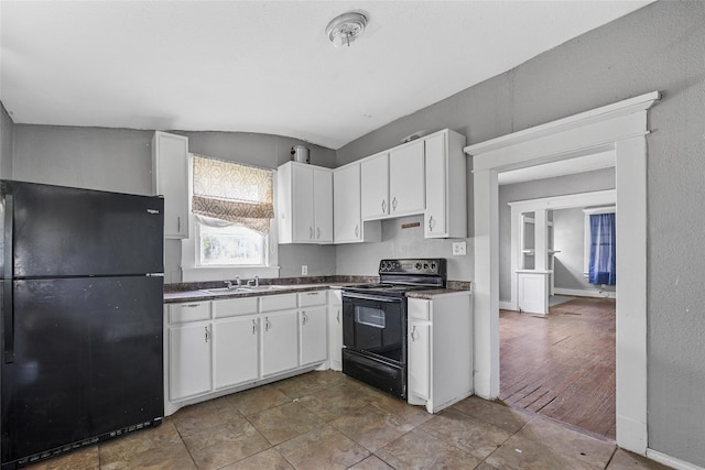 kitchen with white cabinets, a sink, dark countertops, baseboards, and black appliances