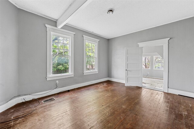 spare room featuring a textured ceiling, visible vents, plenty of natural light, and wood-type flooring