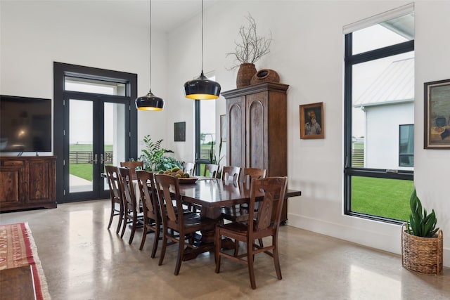 dining space with concrete flooring, a high ceiling, and french doors