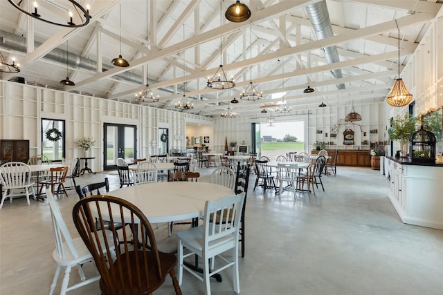 dining room featuring high vaulted ceiling, finished concrete flooring, a wealth of natural light, and a chandelier