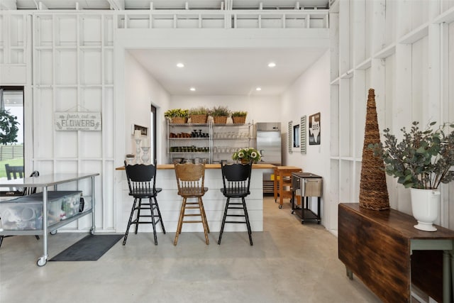 bar with concrete floors, recessed lighting, and stainless steel built in refrigerator