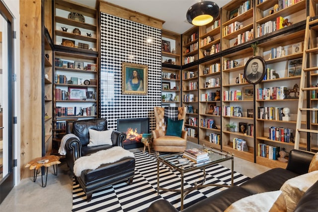 living area with a tiled fireplace and wall of books