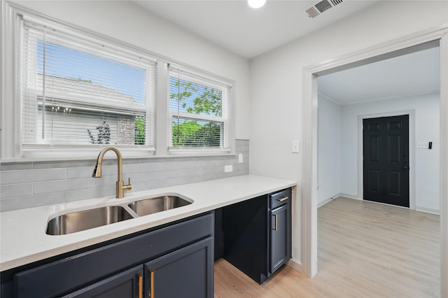 kitchen featuring a sink, visible vents, backsplash, and light countertops
