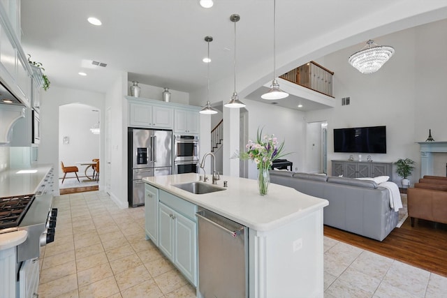 741 Almeda Ln, Prosper, TX 75078 - kitchen featuring stainless steel appliances, a sink, arched walkways, light countertops, and an island with sink