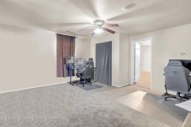 unfurnished office featuring a ceiling fan, baseboards, carpet, and a textured ceiling
