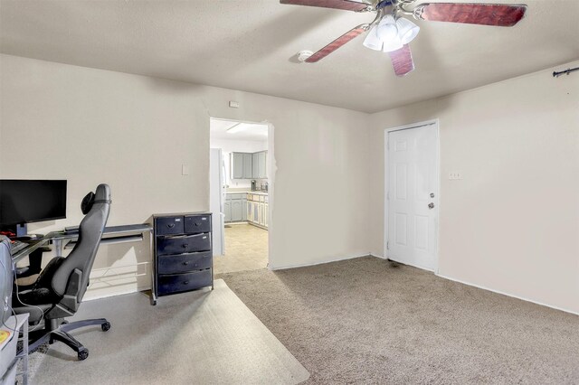 carpeted home office featuring a ceiling fan